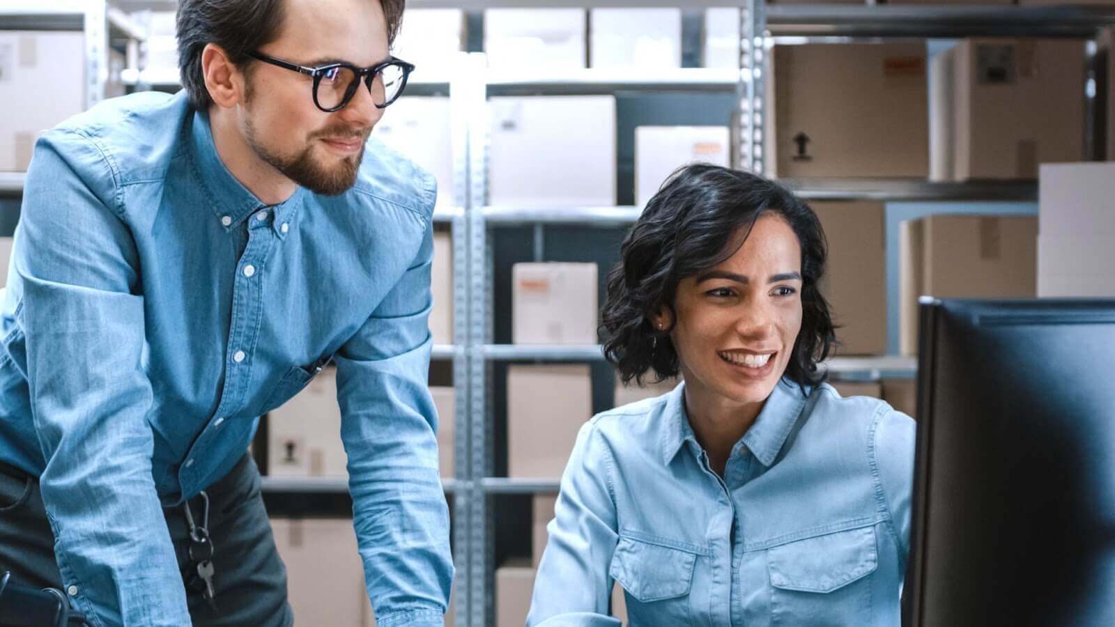 Man and woman in warehouse looking at computer screen