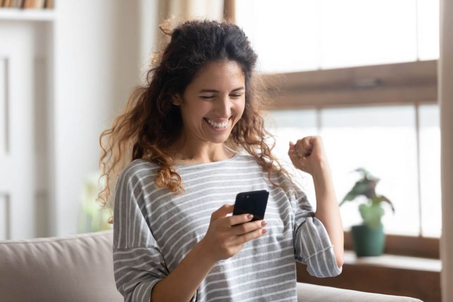 Woman pumping her fist in excitement while looking at her phone
